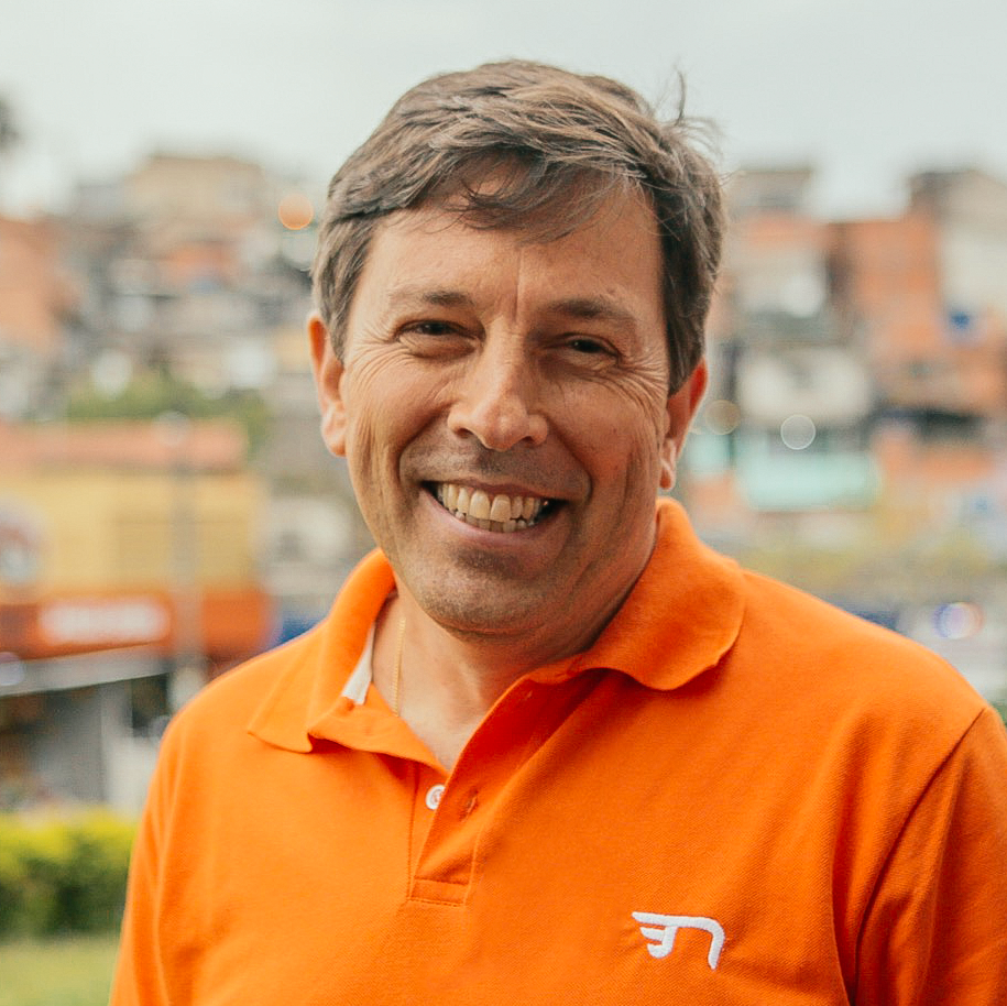Foto: João Amoêdo sorrindo com camisa laranja e fundo desfocado.