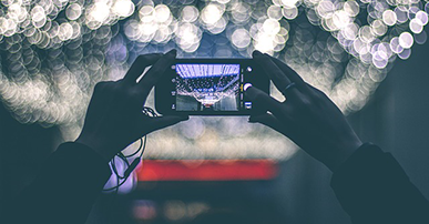 Foto: mãos segurando um celular e tirando uma foto.