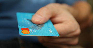 Imagem: mão segurando um cartão de crédito azul.