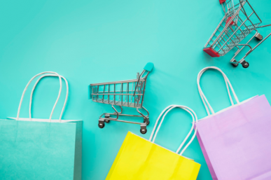 Imagem: sacolas de compras e miniaturas de carrinhos em um fundo azul claro. consumidores.