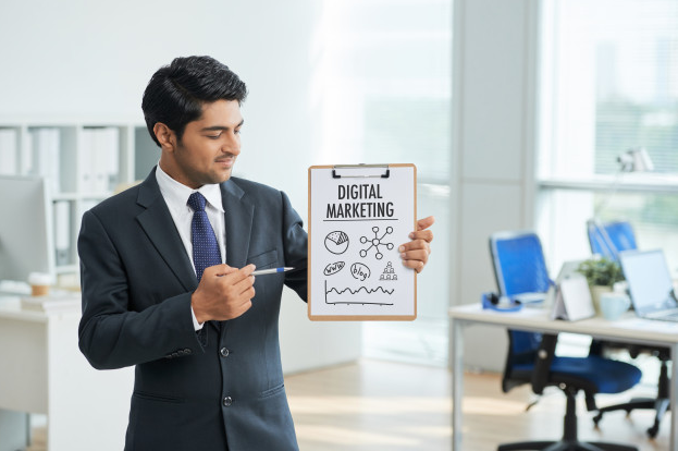 Imagem: homem de terno em uma agência, segurando uma prancheta com as palavras "marketing digital".