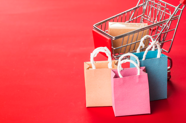 Imagem: fundo vermelho com mini carrinho de compras e sacolas. marketing digital.